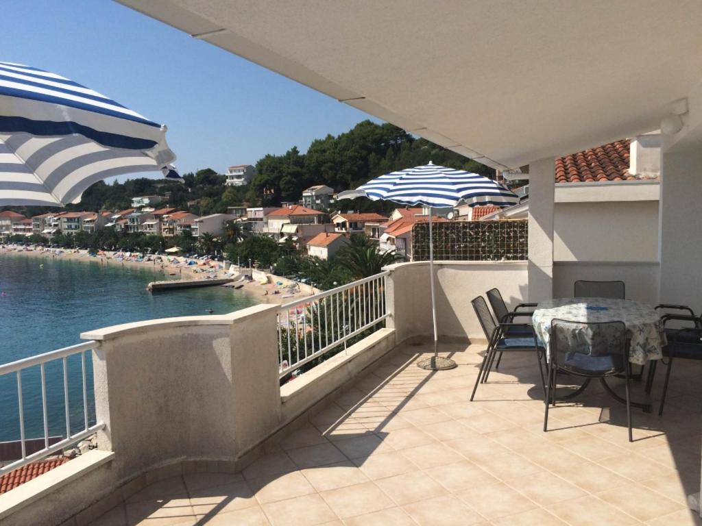 einen Balkon mit einem Tisch und Stühlen sowie Blick auf das Wasser in der Unterkunft Apartment in Podgora with sea view, terrace, air conditioning, WiFi 134-3 in Podgora