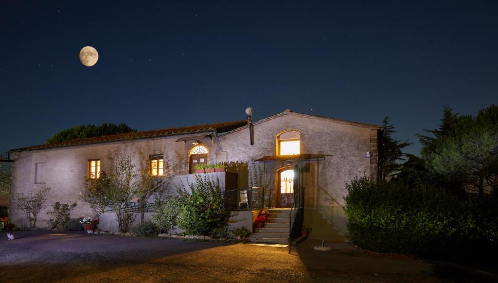 沃爾泰拉的住宿－Podere San Francesco，天空中月亮的夜晚房屋