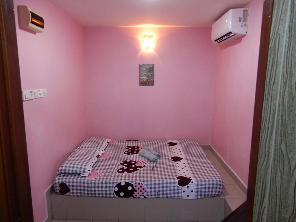 um pequeno quarto com uma cama num quarto cor-de-rosa em LA MOTEL em Sungai Petani