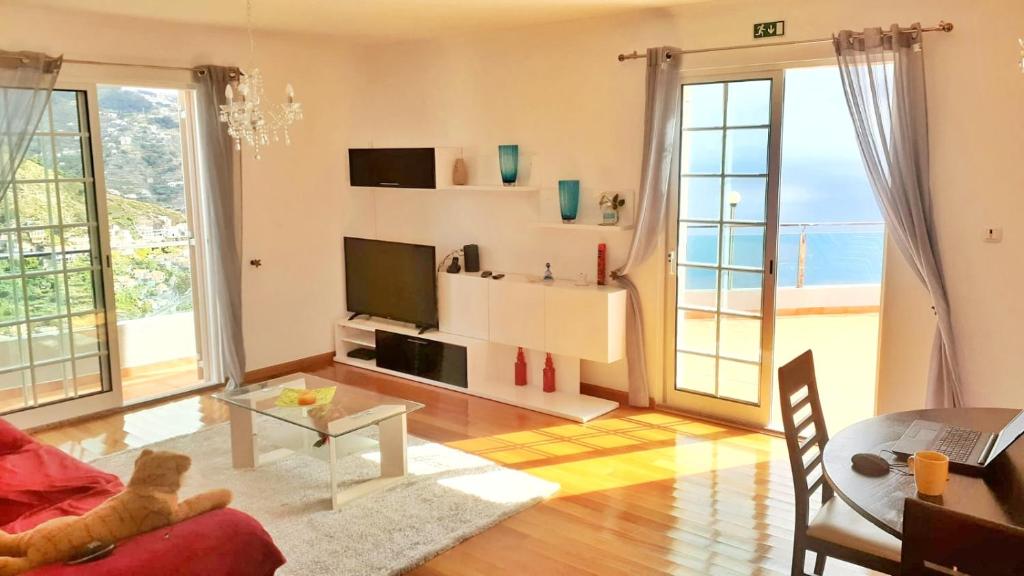 a living room with a television and large windows at Madeira Island Villa Oceane Ribeira Brava in Ribeira Brava