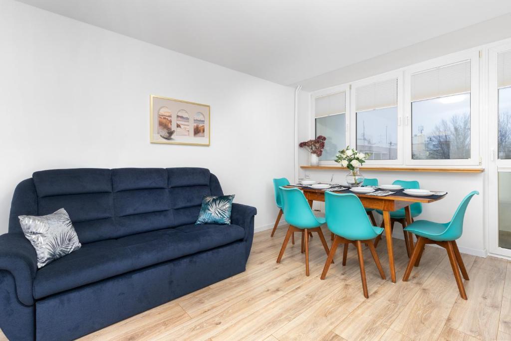 a living room with a blue couch and a table and chairs at City Center Apartment Gdynia by Renters in Gdynia