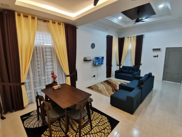 uma sala de estar com uma mesa e um sofá azul em Nawra Homestay Besut, Terengganu em Kampung Raja