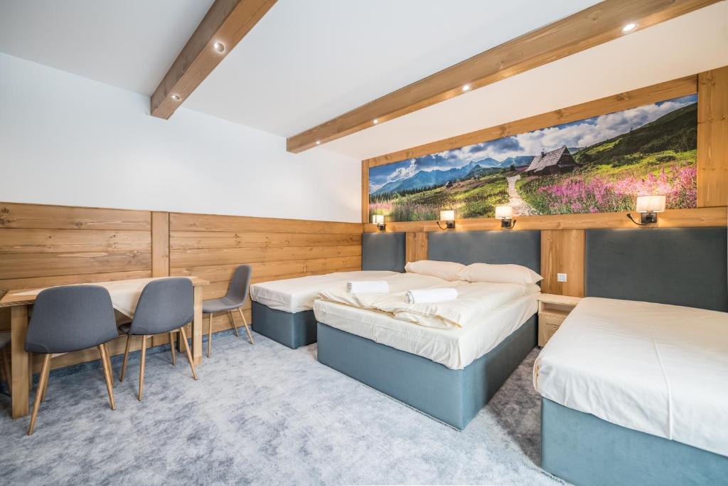 een kamer met 2 bedden en een tafel en stoelen bij Willa Taterniok - pokoje z widokiem na Tatry in Czarna Góra