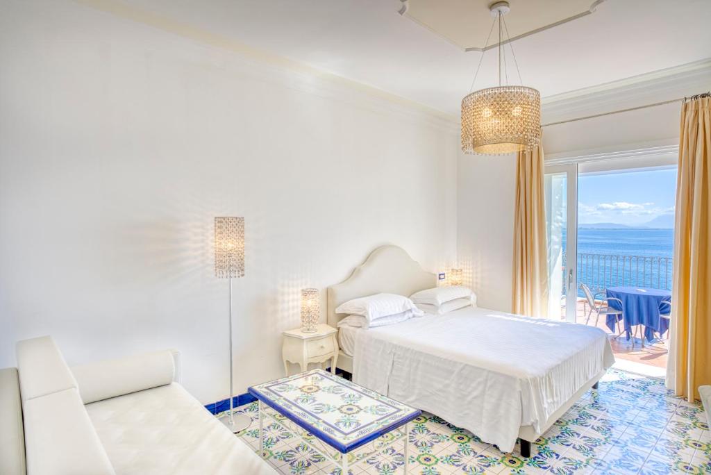 a white bedroom with a bed and a balcony at Hotel Cetus in Cetara