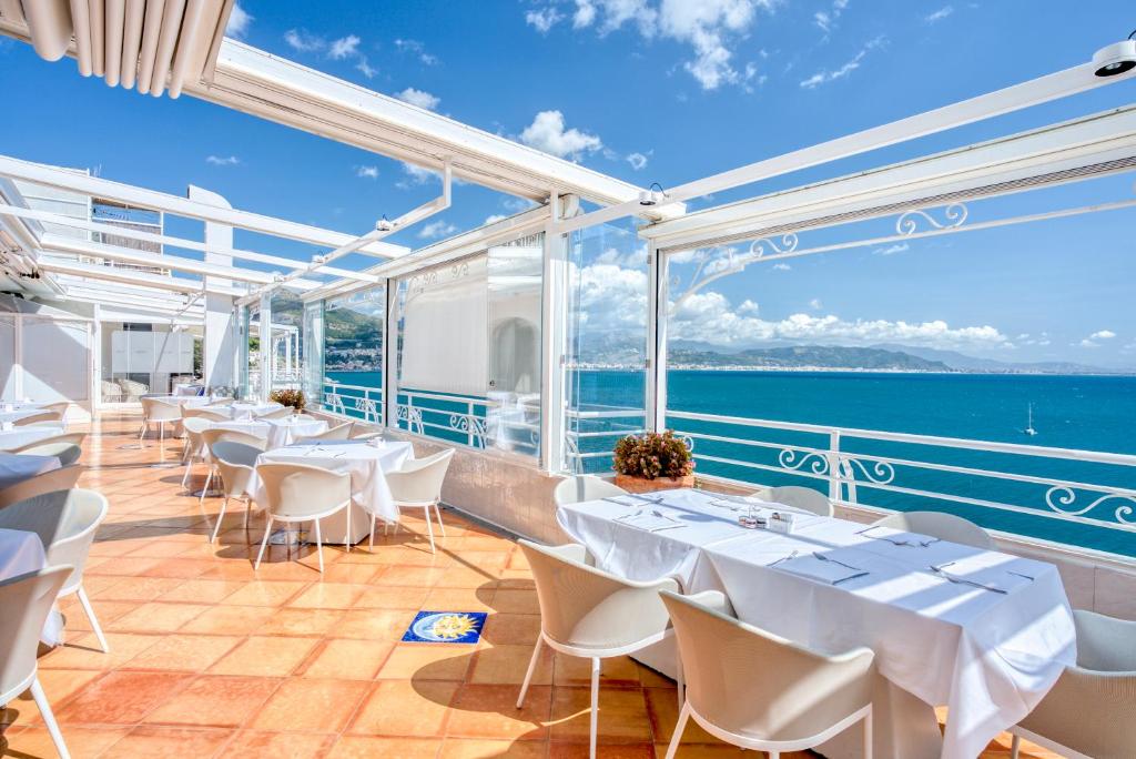 a restaurant with white tables and chairs and the ocean at Hotel Cetus in Cetara