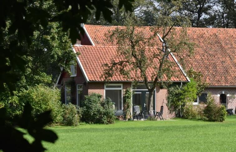 a house with a red roof and a green yard at Vakantiehuisje op de Rotmanshoeve in Kotten