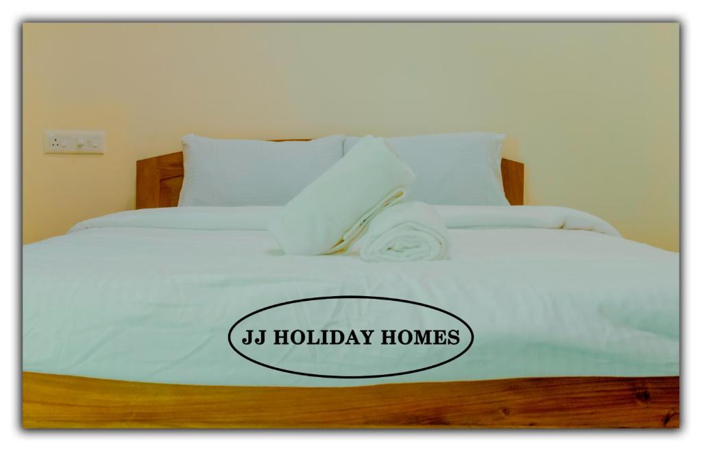 een wit bed met een bord dat vakantiehuizen leest bij JJ Holiday Homes in Canaguinim