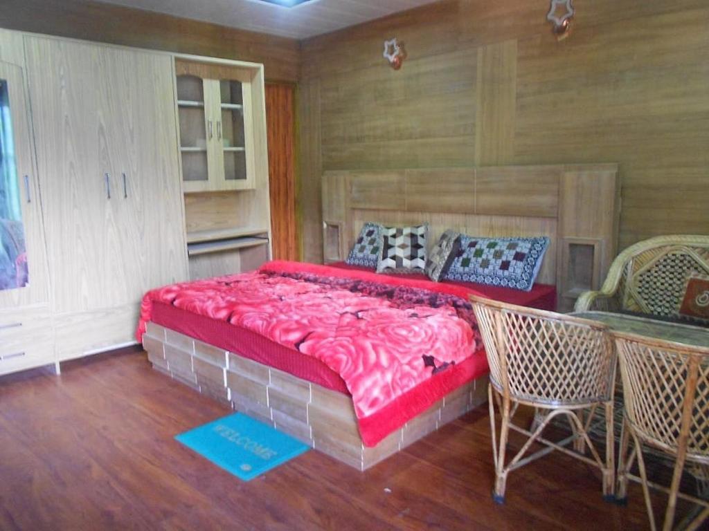 1 dormitorio con 1 cama grande, mesa y sillas en Nandan Kanan Auli Resort, en Jyotirmath