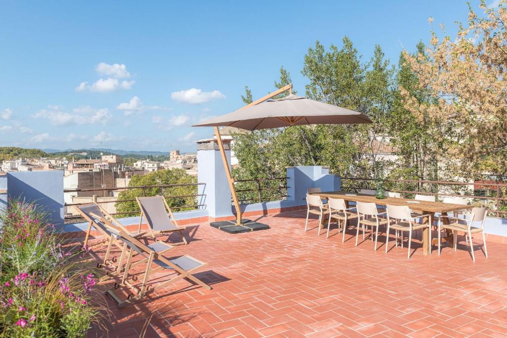 eine Terrasse mit einem Tisch, Stühlen und einem Sonnenschirm in der Unterkunft LaComuna City Oasis in Girona