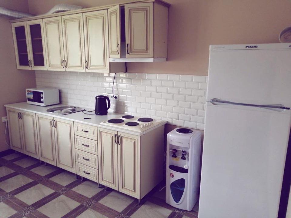 a kitchen with white cabinets and a white refrigerator at Диас in Sukhum