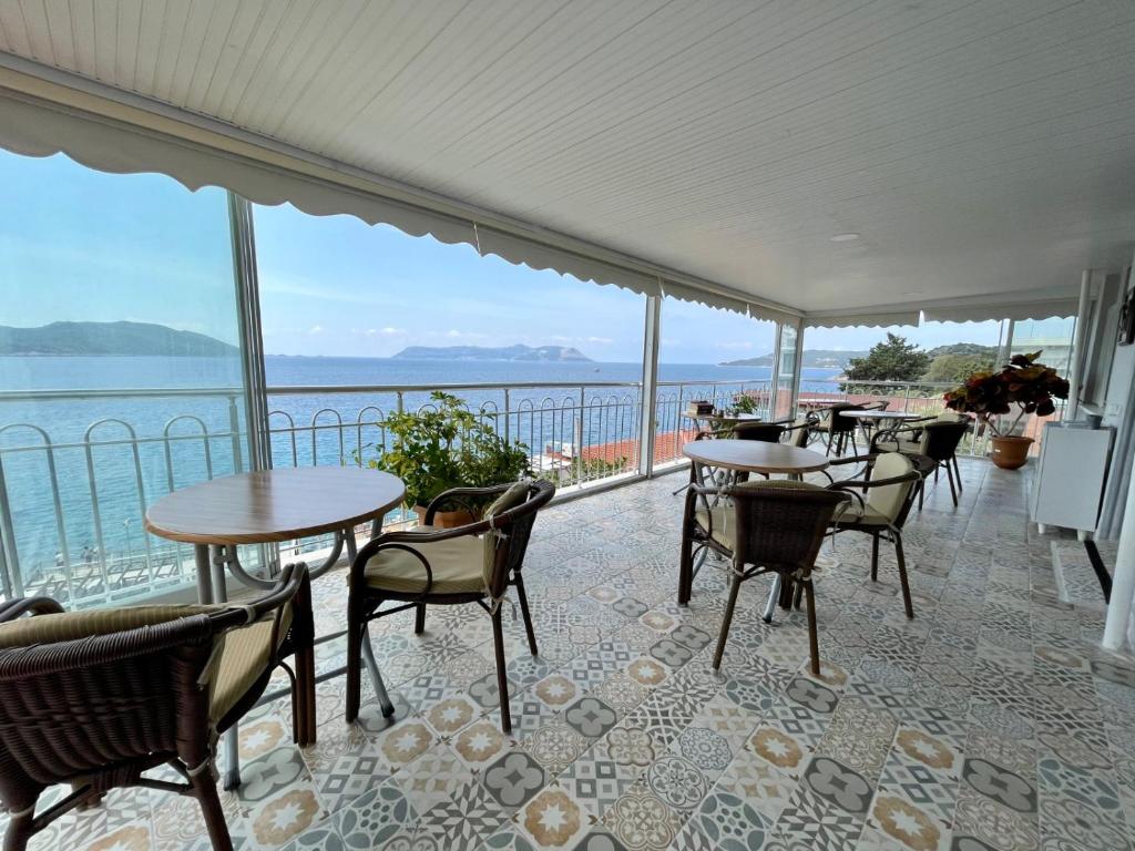 a patio with tables and chairs and a view of the water at YALI PANSİYON in Kas
