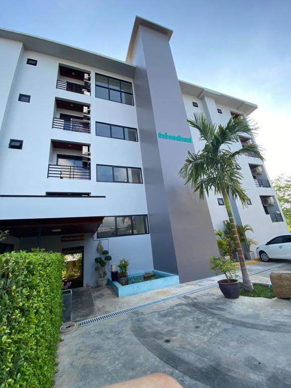 a building with a palm tree in front of it at Tha-ruea Residence in Thalang