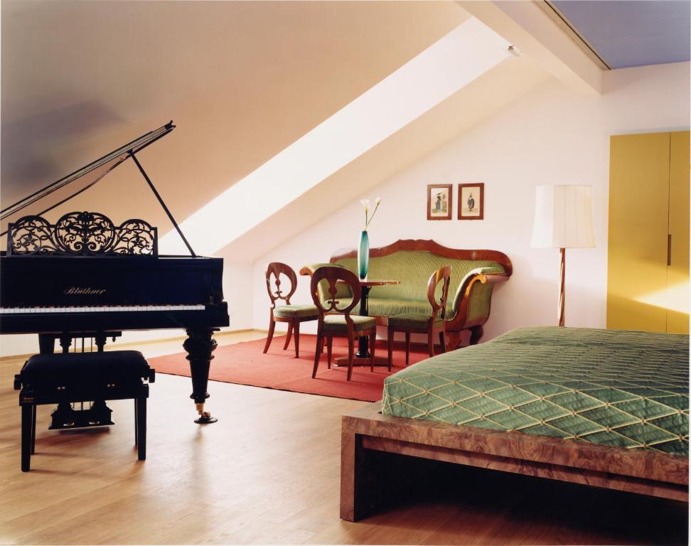 a living room with a piano and a bed at Hotel Greif in Bolzano