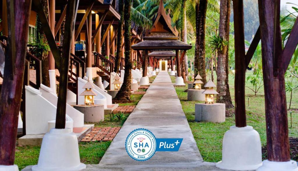 una pasarela que conduce a un complejo con palmeras en C&N Kho Khao Beach Resort - SHA Plus, en Ko Kho Khao