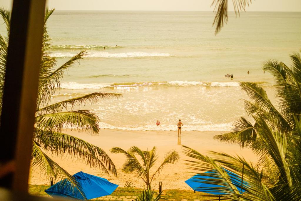 uma vista para uma praia com guarda-sóis azuis e para o oceano em The Seascape em Matara