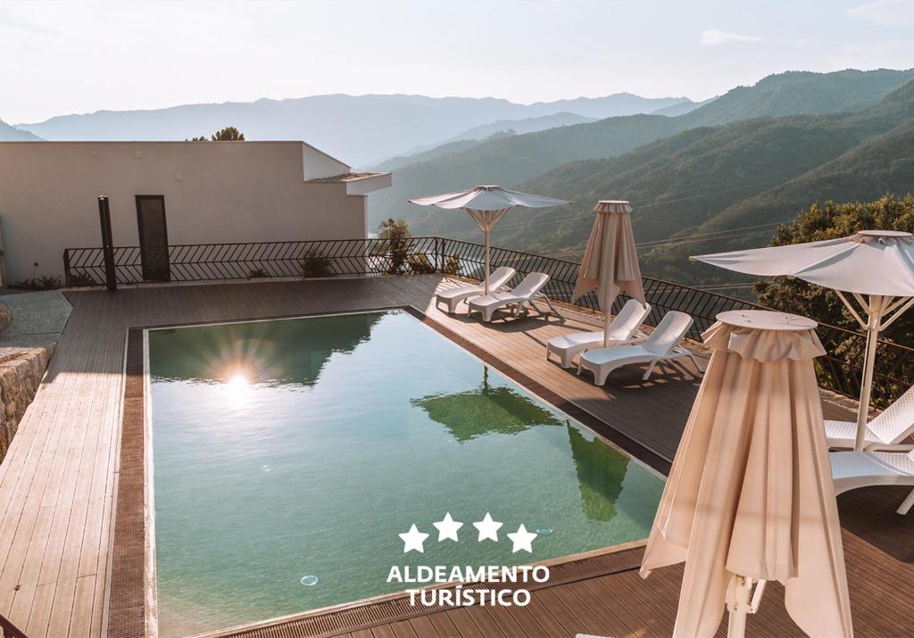 uma piscina com cadeiras e guarda-sóis num resort em Encosta de Louredo by Pousadela Village em Vieira do Minho