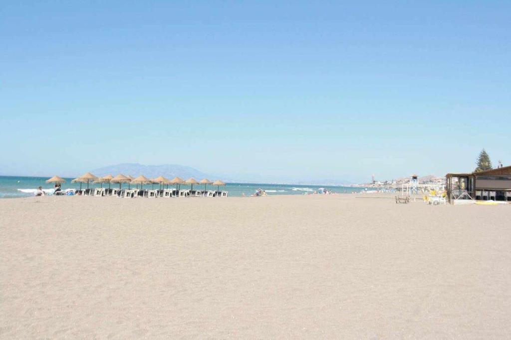 a beach with umbrellas and chairs and the ocean at Mshome Mirada al Mediterráneo in Rincón de la Victoria