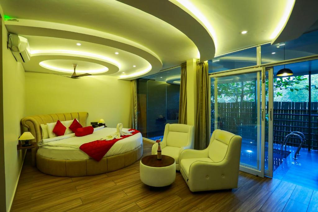 a bedroom with a bed and two chairs in it at Kuruva Island Resort And Spa - By KABINI BREEZE, Wayanad in Mananthavady