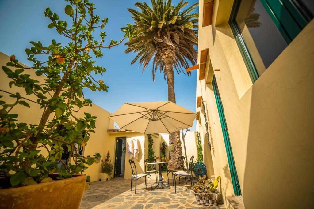 eine Terrasse mit einem Tisch mit einem Sonnenschirm und einer Palme in der Unterkunft Casa Chalet La Casita in Tabayesco