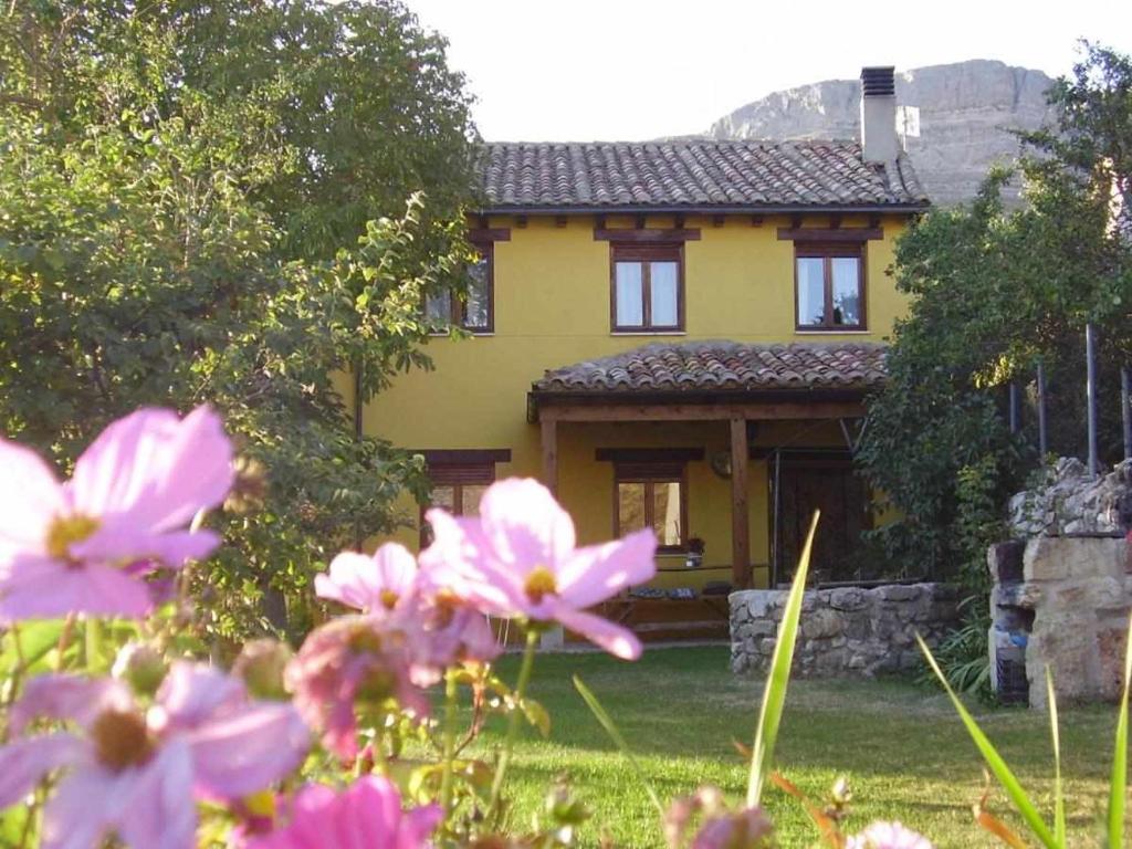 una casa amarilla con flores rosas delante en Casa Rural El Hidalgo, en Amaya