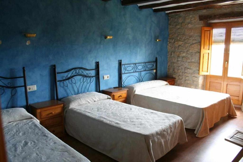 três camas num quarto com paredes azuis em Ca lAntic Joanet em Mirambell