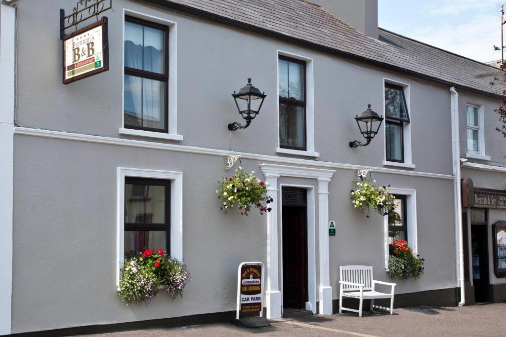 a white building with flowers in the windows at Brennan's Accommodation Glenties in Glenties