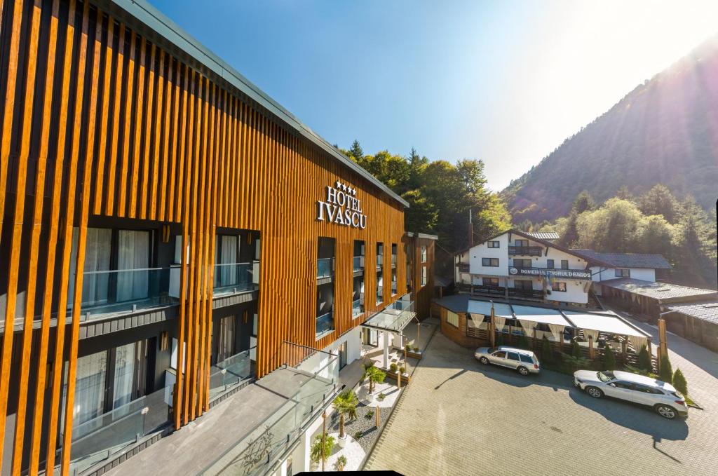 a yellow building with cars parked in a parking lot at Hotel Ivascu in Moisei