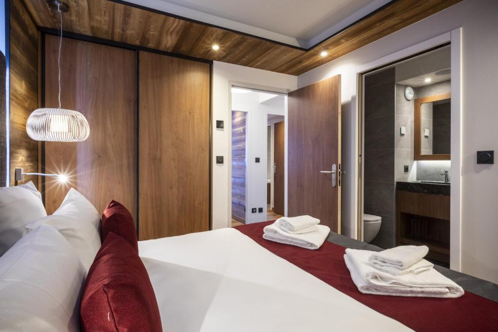 a bedroom with a large white bed and a bathroom at Les Balcons Platinium Val Cenis in Lanslevillard