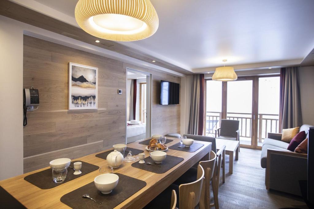 a dining room with a table and a living room at Les Balcons Platinium Val Cenis in Lanslevillard