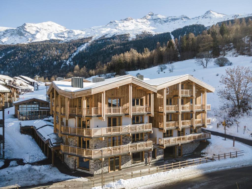a large wooden house in the snow with mountains at Les Balcons Platinium Val Cenis in Lanslevillard