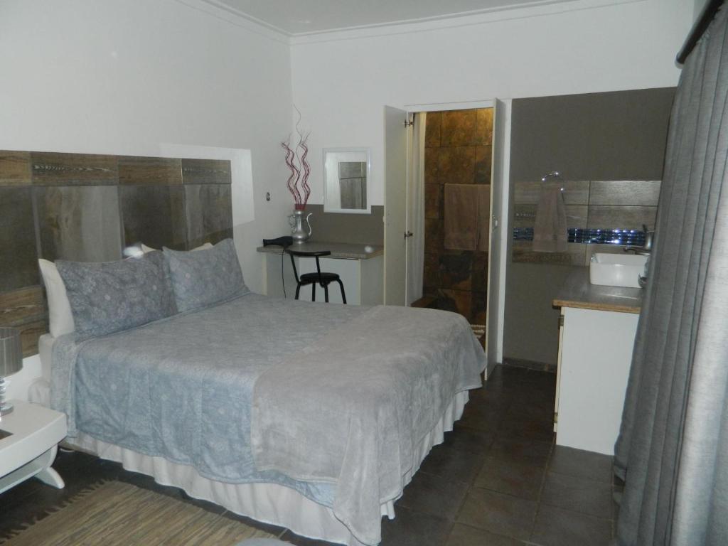 a bedroom with a bed and a small kitchen at Aub Guesthouse - Mariental in Mariental