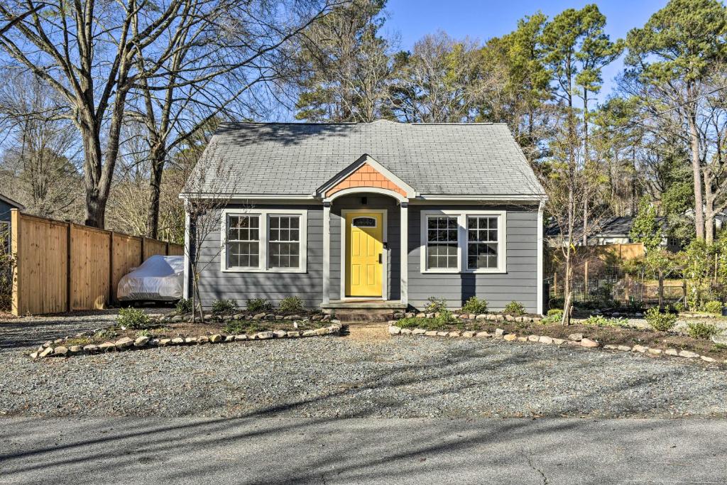 a small house with a yellow door in a driveway at Renovated Carrboro House with Deck and Fire Pit! in Carrboro