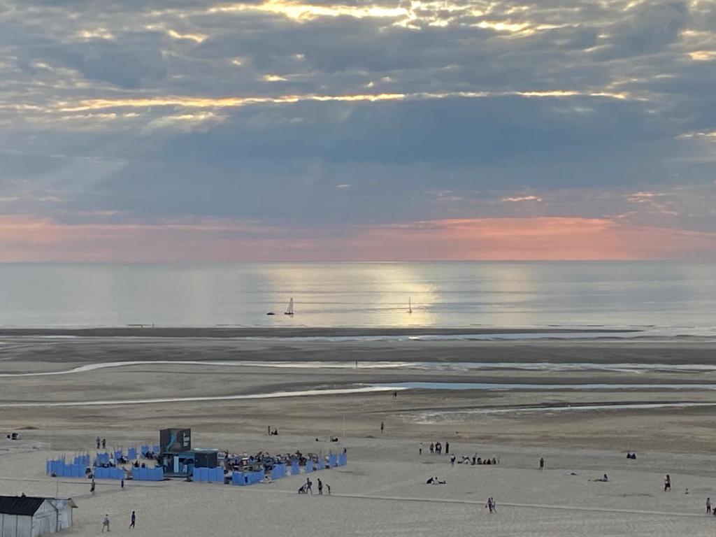 um grupo de pessoas em uma praia com o oceano em Marina em Le Touquet-Paris-Plage