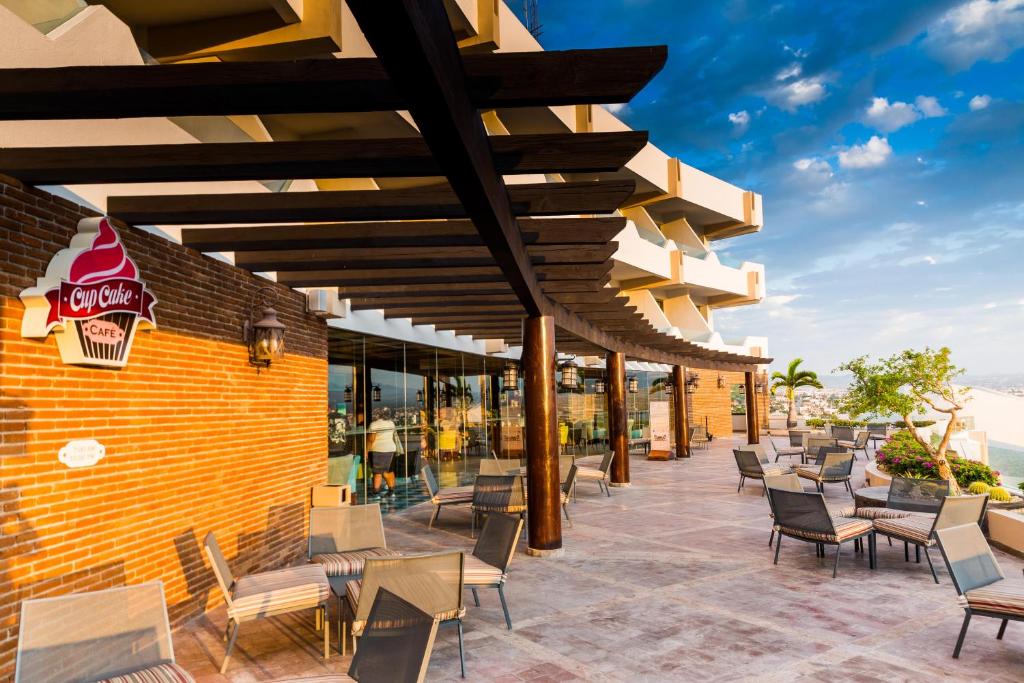 Outdoor bar and seating area with brick wall, wooden pergola, and ocean view.