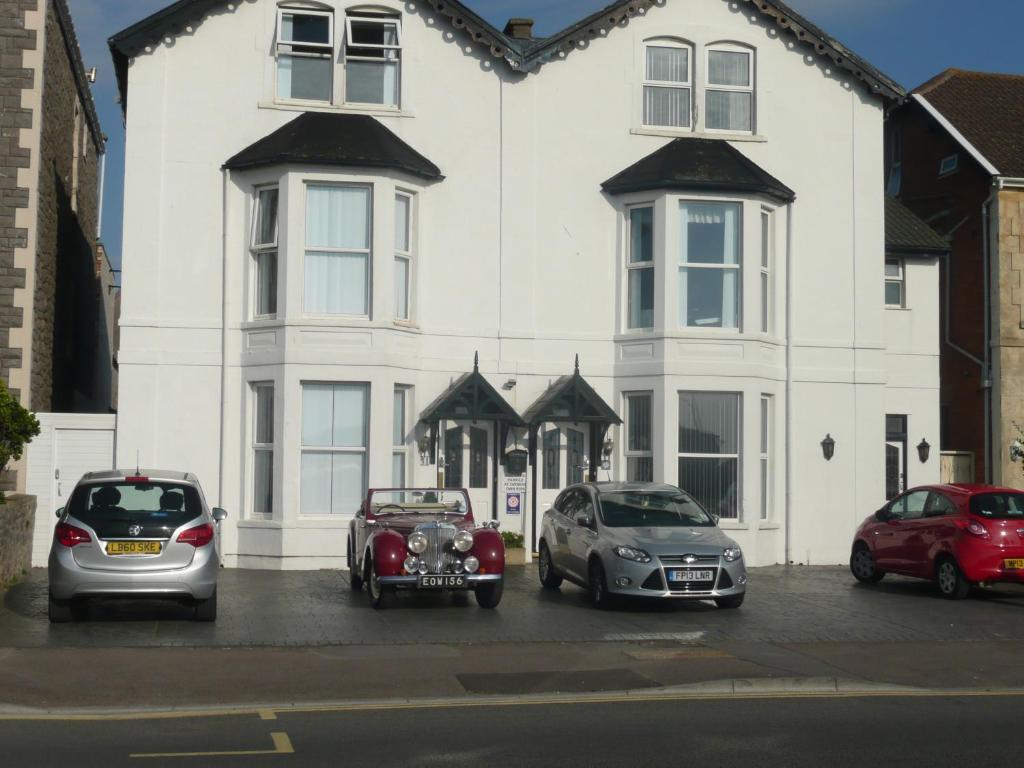 drie auto's geparkeerd voor een wit huis bij The Kyrenia in Weston-super-Mare