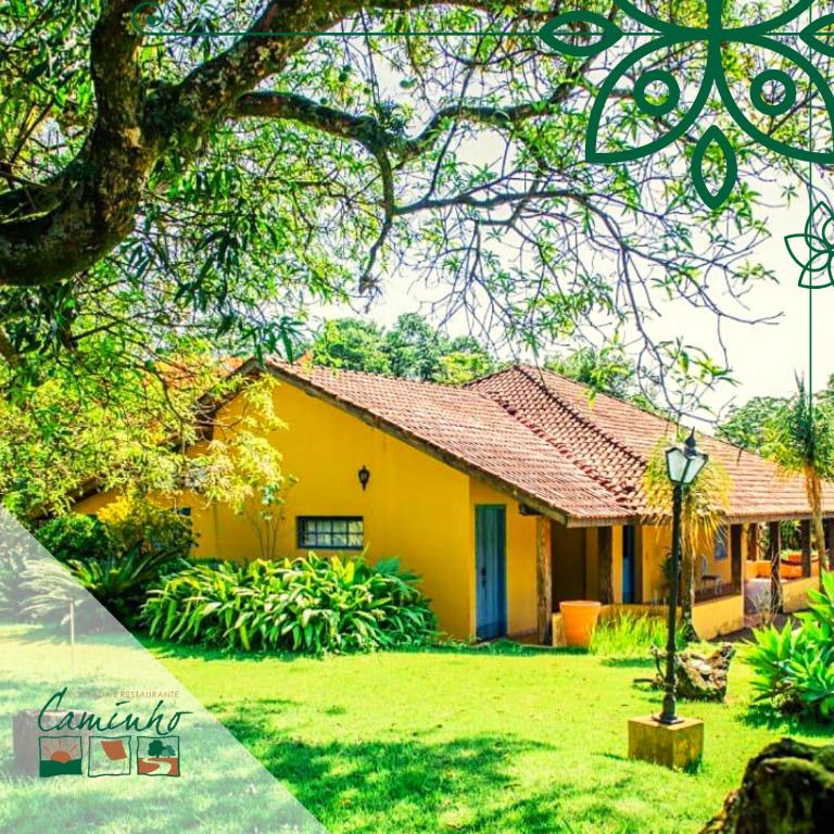 a yellow house in a yard with a tree at Pousada No Caminho in Tambaú