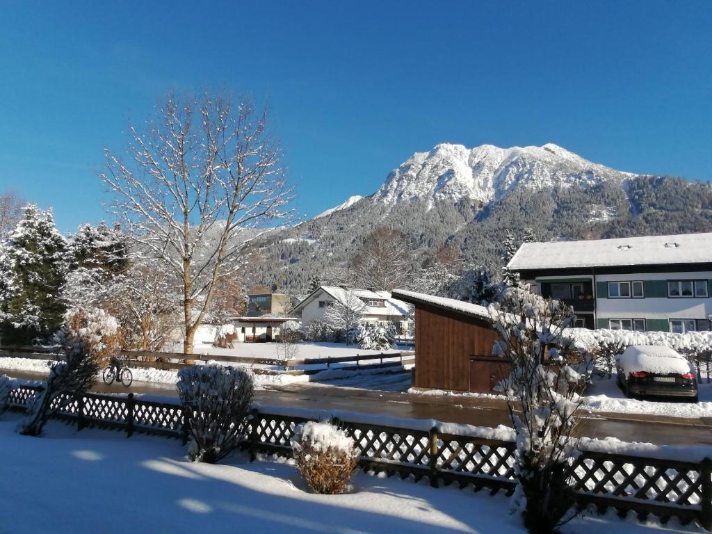 une maison sous la neige avec une montagne en arrière-plan dans l'établissement Ferienwohnung Rubihornblick, à Oberstdorf