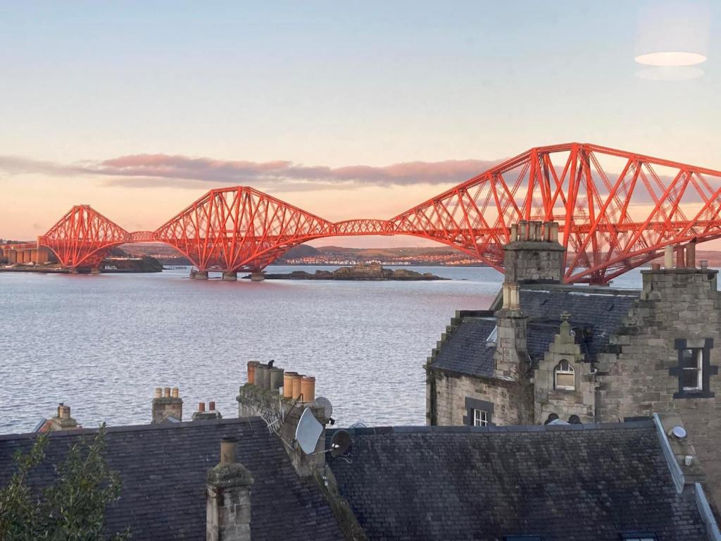 a red bridge over a body of water with buildings at Forth Reflections Self Catering in Queensferry