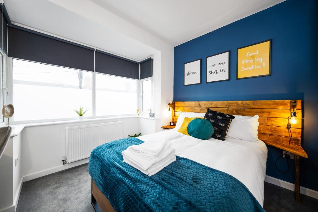 a bedroom with a bed with a blue wall at 7 bedroom house ENSUITE Rooms, fully equipped kitchen, free WIFI, TVs in all rooms CITY CENTRE CLOSE TO A46 Inspire Homes in Coventry