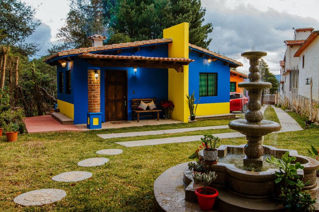 a blue and yellow house with a fountain in the yard at Villas Na in San Cristóbal de Las Casas
