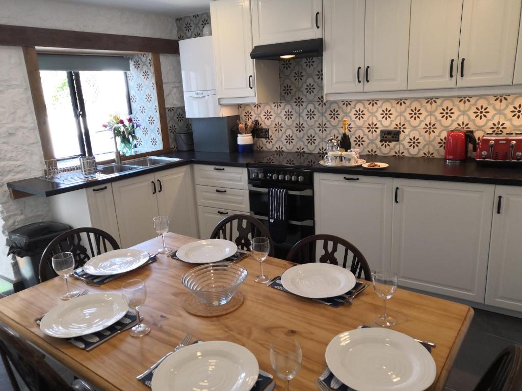 a kitchen with a wooden table with plates and wine glasses at Bowkett Cottage in Cinderford