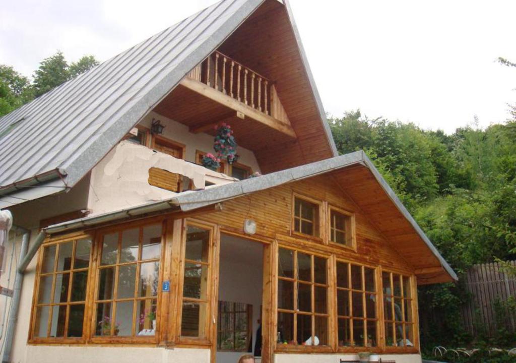 une maison avec des fenêtres en verre et un toit en gambrel dans l'établissement Vila Eva, à Valea Tîrsei