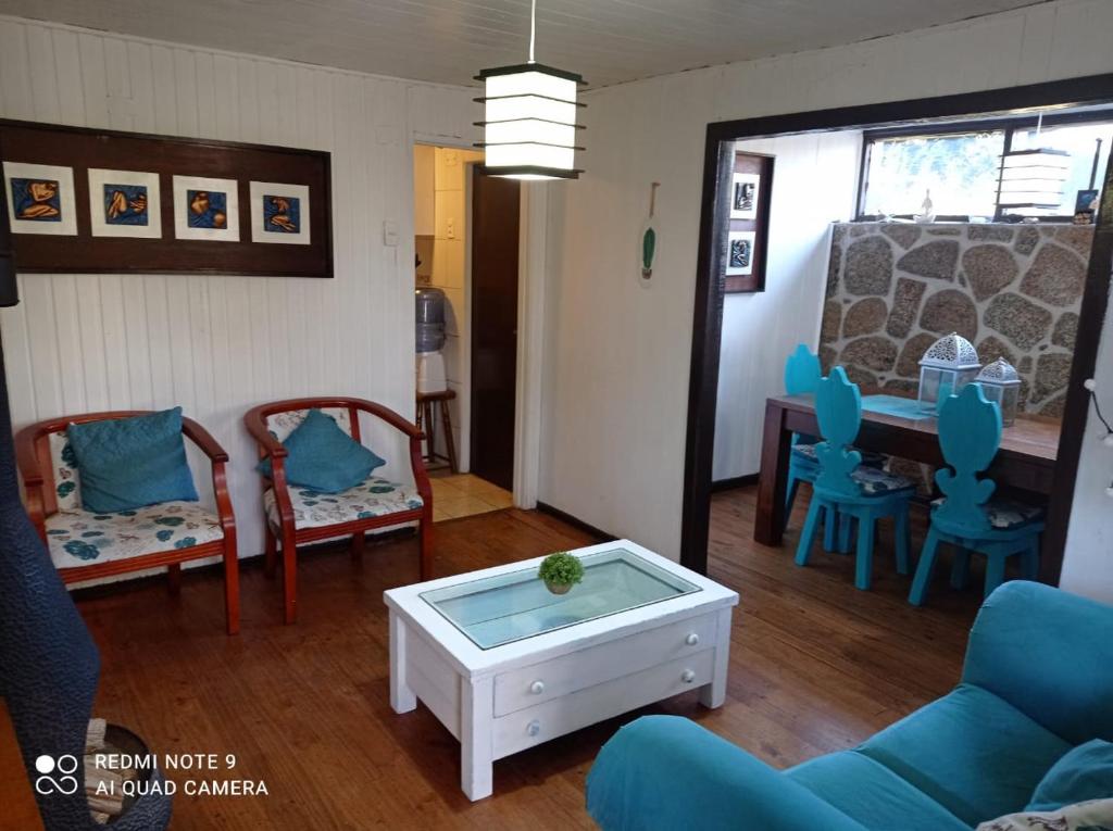 Casa los Lobos a una cuadra de la playa El Quisco في كيسكو: غرفة معيشة مع كراسي زرقاء وطاولة