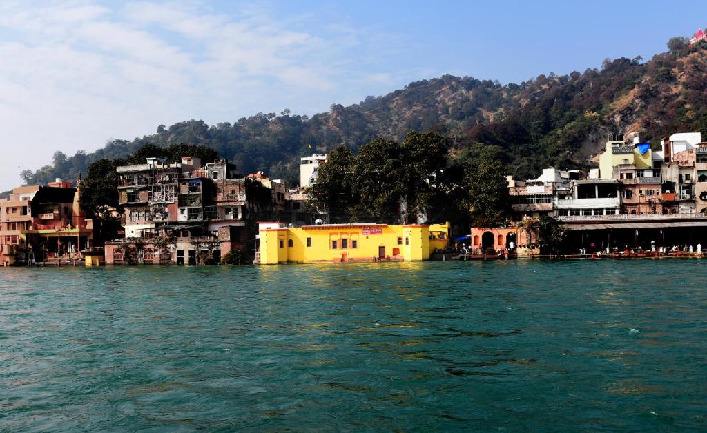 eine Gruppe von Gebäuden am Ufer eines Wasserkörpers in der Unterkunft Patnimal Guesthouse in Haridwar