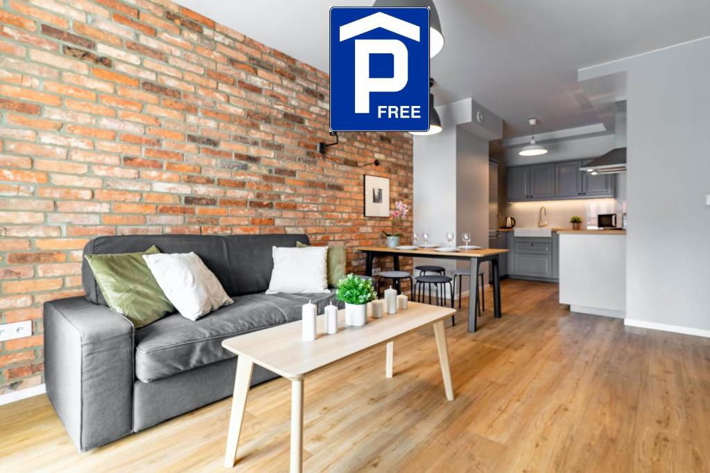 a living room with a couch and a brick wall at WrocApartments StarCenter in Wrocław