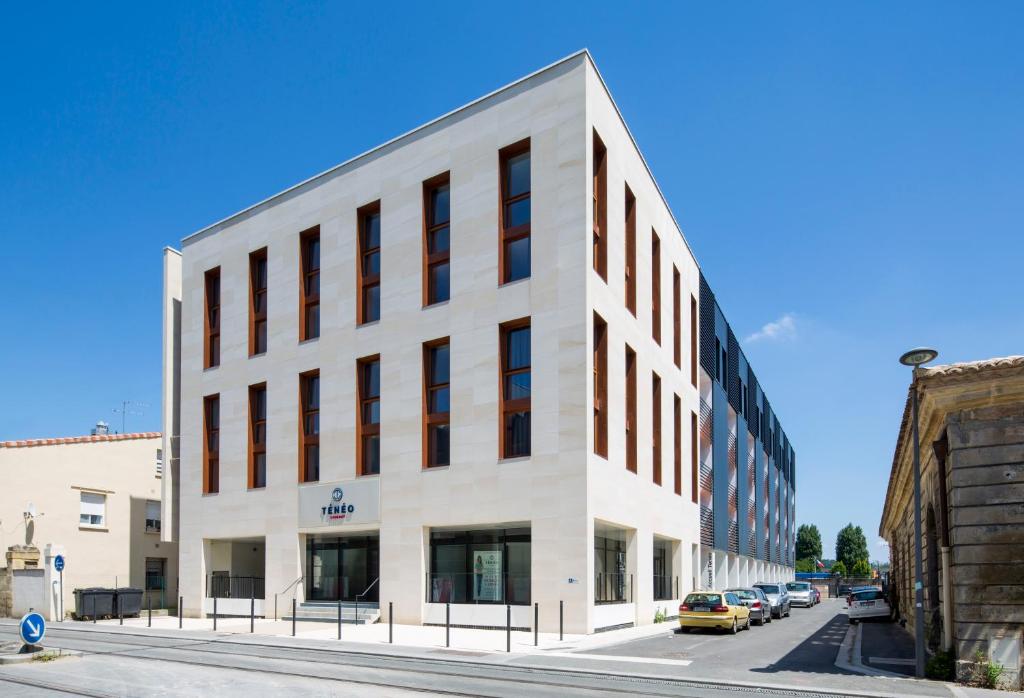 a white building on a street with cars parked at Ténéo Apparthôtel Bordeaux Maritime - Cité du vin in Bordeaux