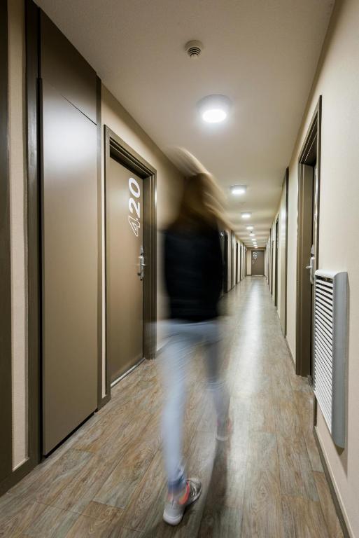 a person walking down a hallway in an elevator at Ténéo Apparthôtel Bordeaux Maritime - Cité du vin in Bordeaux