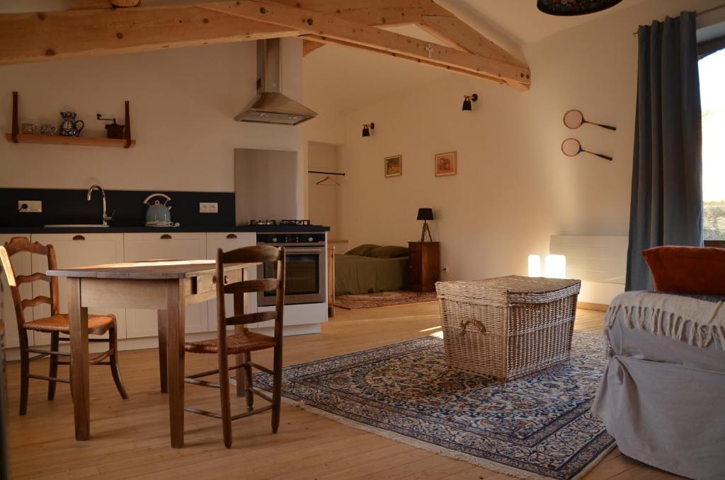 Le Petit Riousset, gîte à la campagne, piscine, petit-dèj في Montvendre: مطبخ وغرفة معيشة مع طاولة وكراسي
