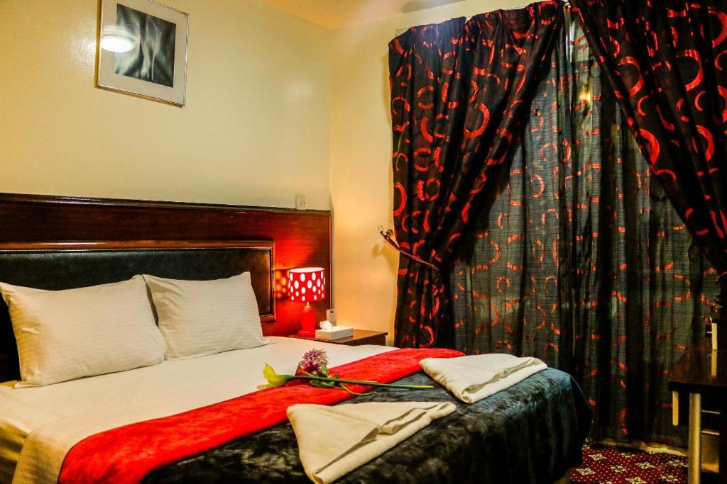 Karoon Hotel في دبي: غرفة نوم مع سرير مع بطانية حمراء عليه