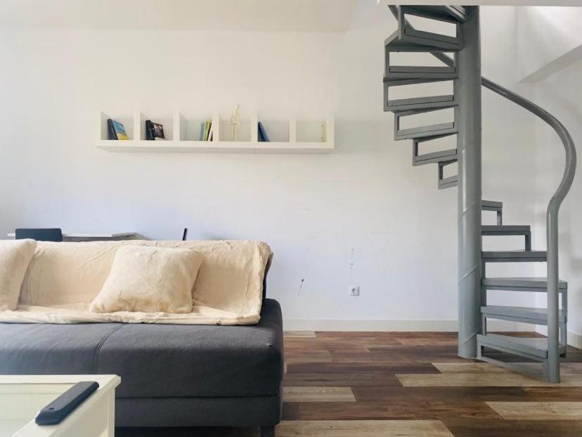 sala de estar con sofá y escalera de caracol en Lovely Triana flat with roof terrace, en Sevilla